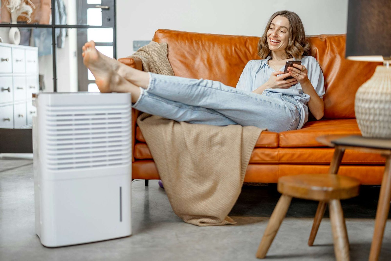 Woman sitting near air purifier and moisturizer appliance